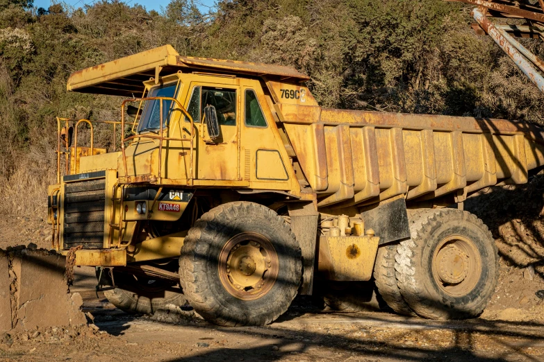 a large yellow dump truck parked on top of a dirt field