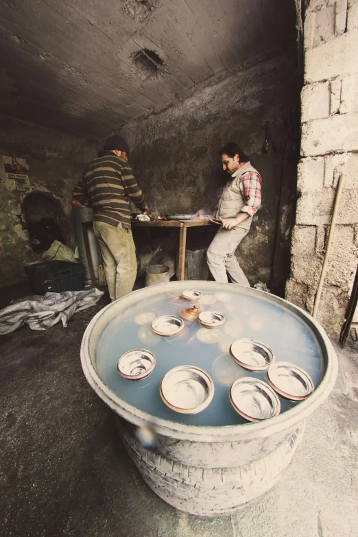 a group of men in a room with large pottery