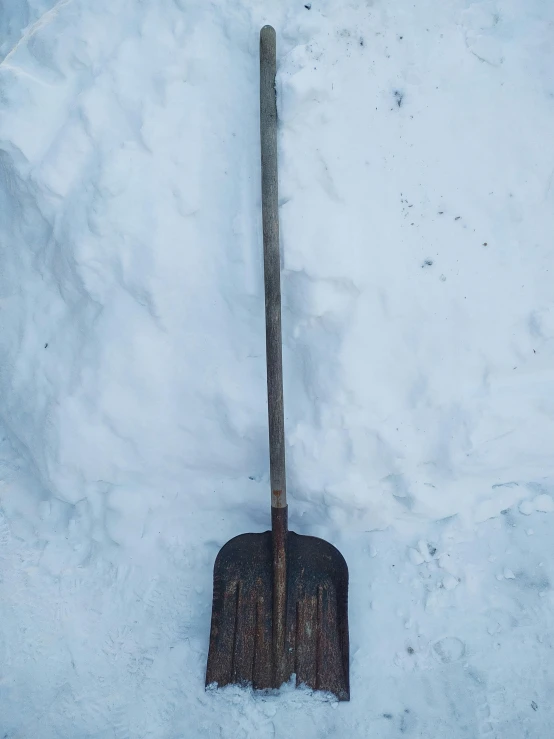 a shovel is in the snow with it's head on top of the shovel