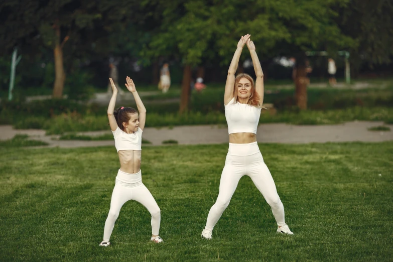 two women doing yoga outdoors on a grassy area