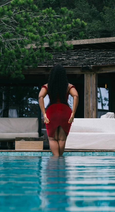 a girl with black hair is posing by the edge of a pool