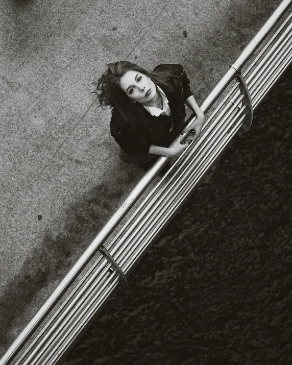 a woman walking down the sidewalk leaning on the metal fence