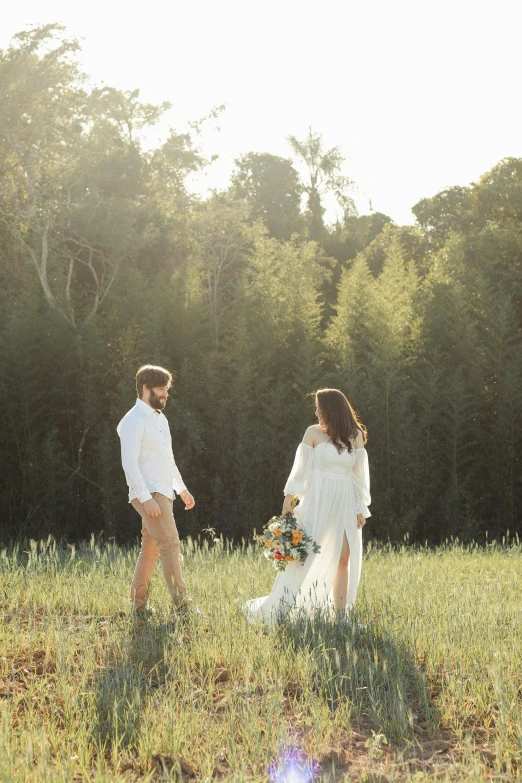 two people dressed in white walking through a grassy field