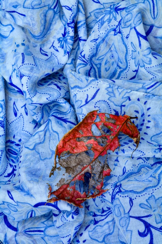 a leaf is laying on some fabric in the wind