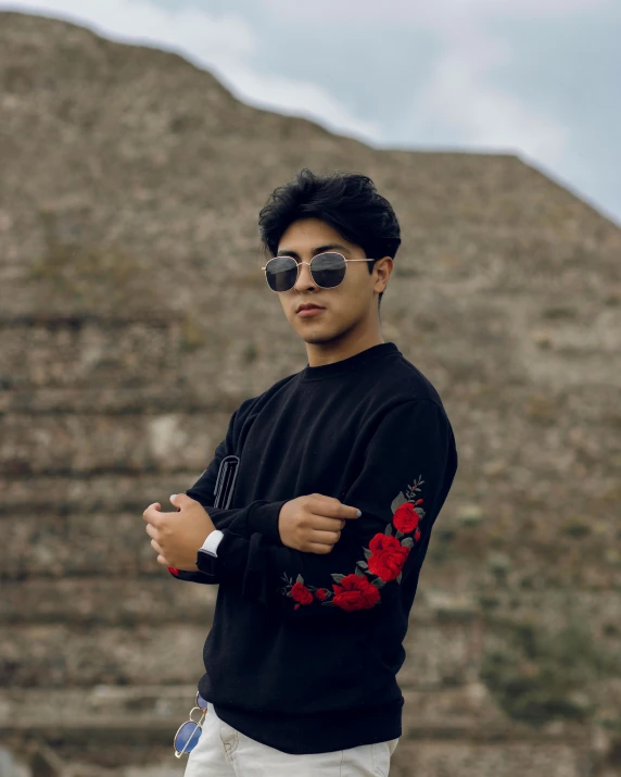 a young man is standing outside wearing sunglasses