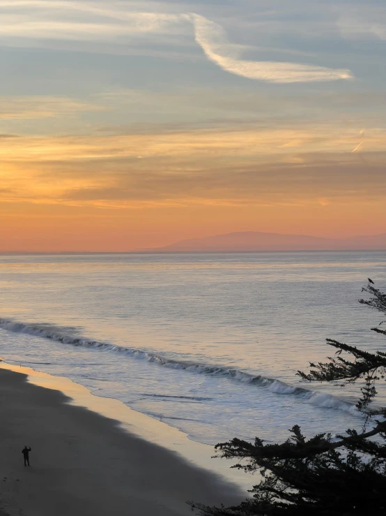 two men walking on a beach near the ocean