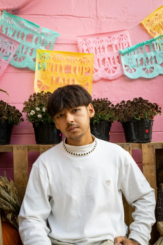 a young man sitting on a bench next to plants