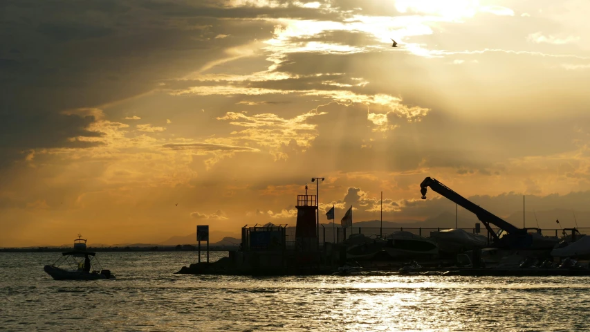 the sun is coming out over a harbor