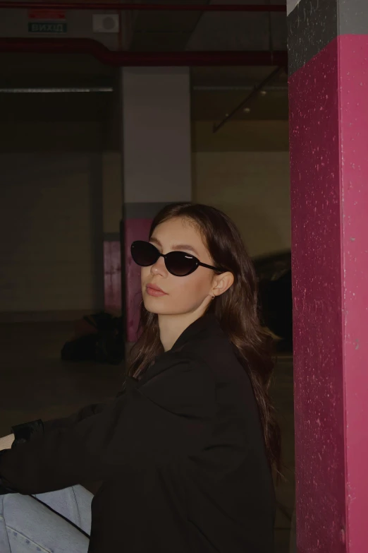 a girl in sunglasses poses for the camera in a dark room