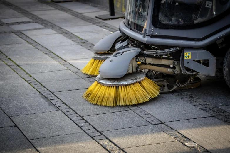 a floor cleaner brush laying on top of a dirty street