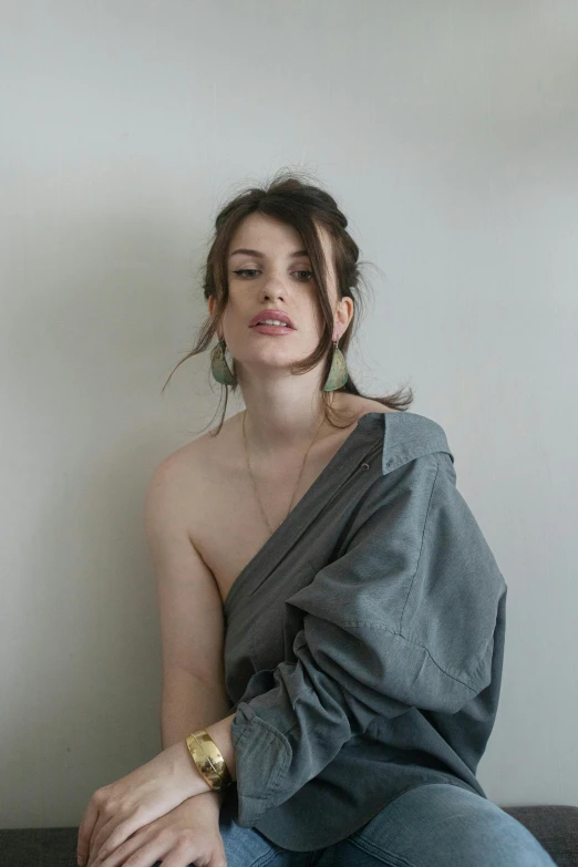 a young woman wearing large, gold - trimmed earrings is sitting on a bed