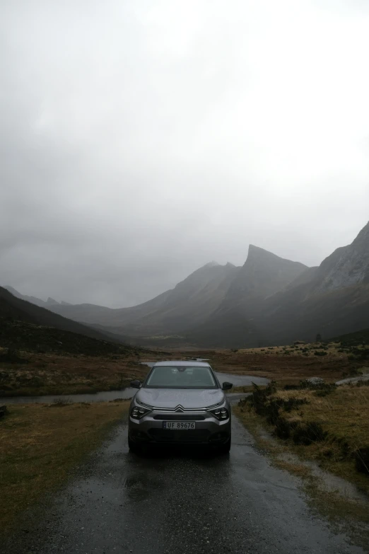 a car on a road near mountains on a cloudy day