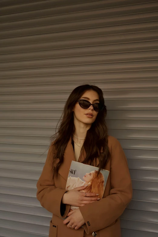 a woman is leaning against a wall with a book in her hands