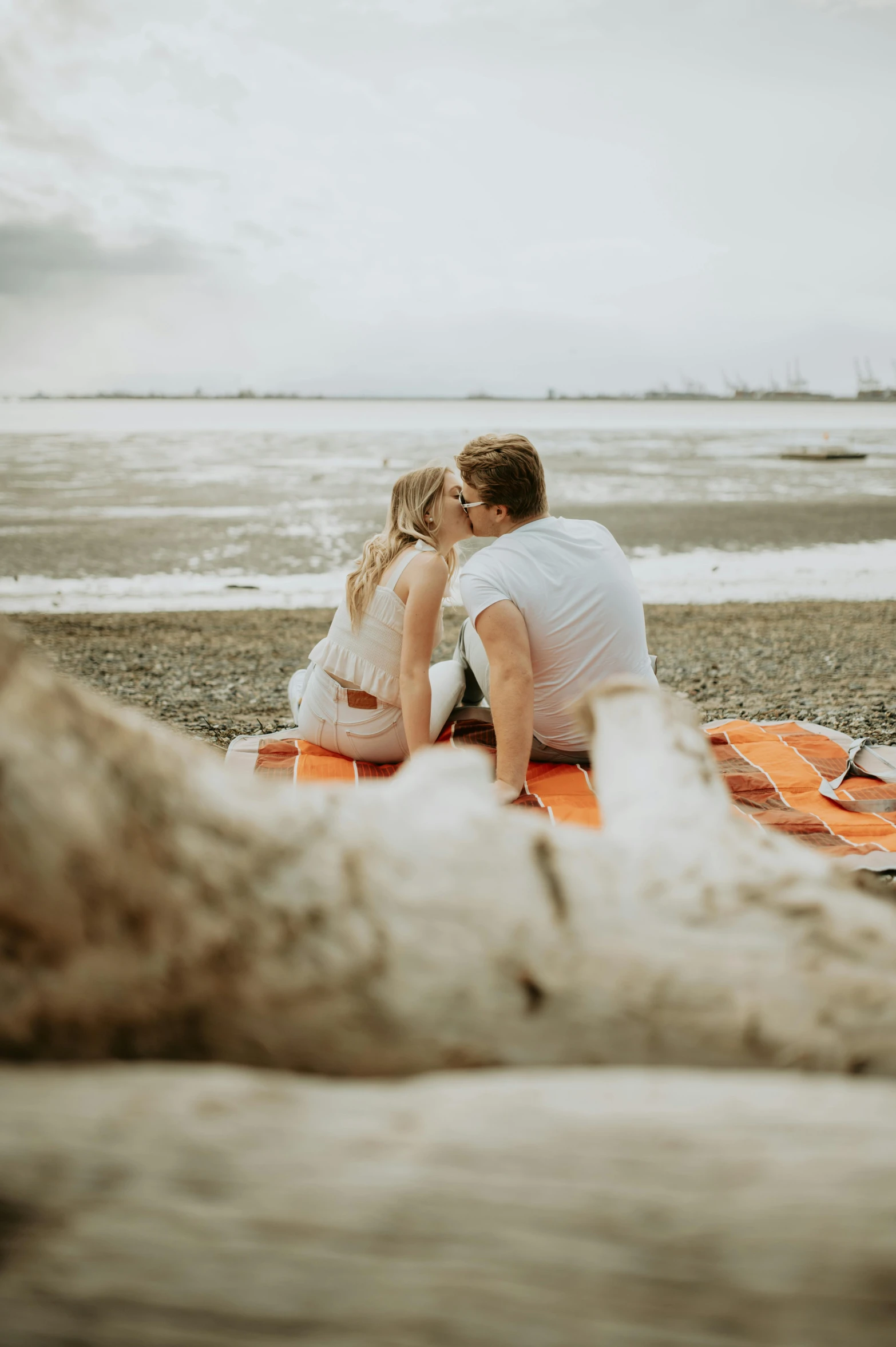 a couple sitting on top of a surfboard on a beach