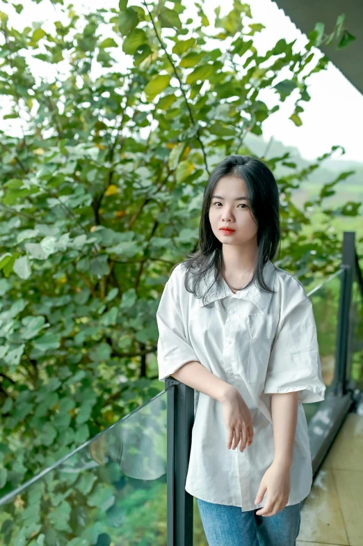 a young woman wearing jeans and an over sized top posing on the balcony