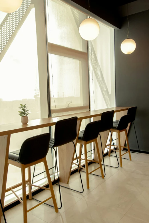 a long wooden table with black chairs next to windows