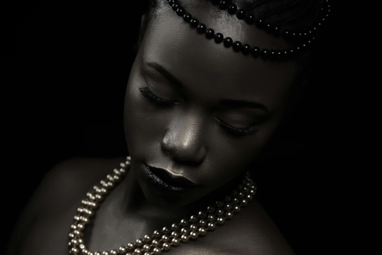 a black woman is dressed in silver with pearls on her necklace and has her eyes closed