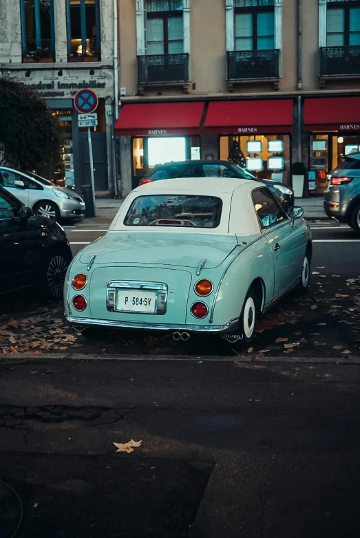 an old car parked at the curb beside a street