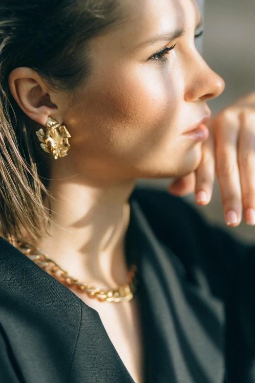 a woman with black jacket and gold earrings