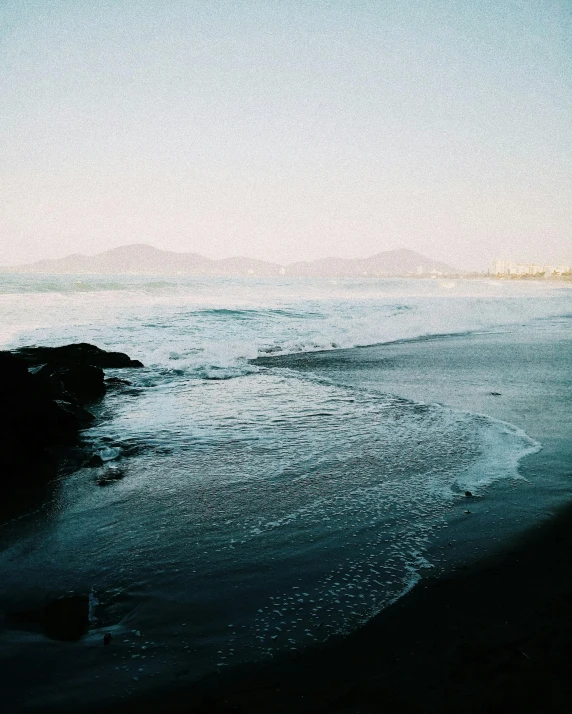 the ocean has some small waves coming in on the shore