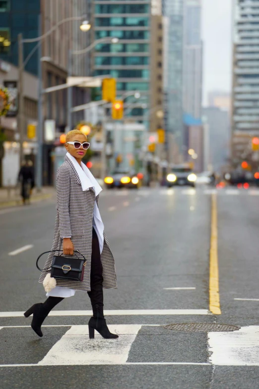 a lady crossing a street with a plaid coat and hat