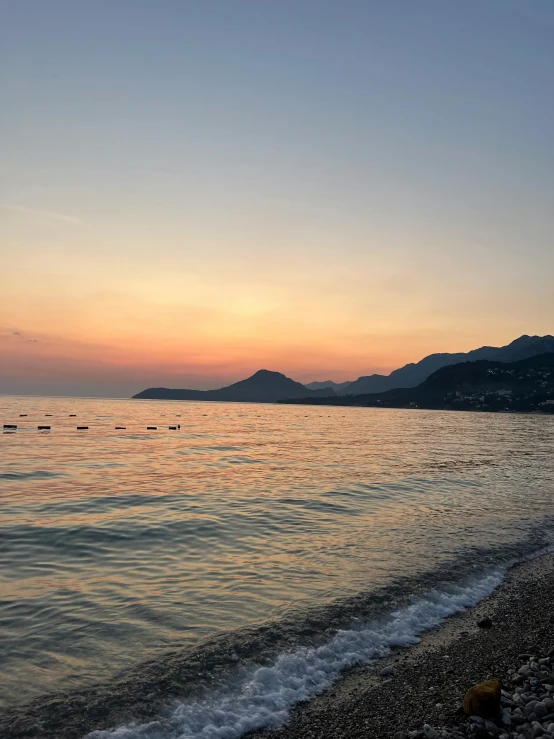 the sunset is going on at a beach near a body of water