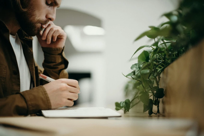 a man looking at soing while he's writing on a notepad