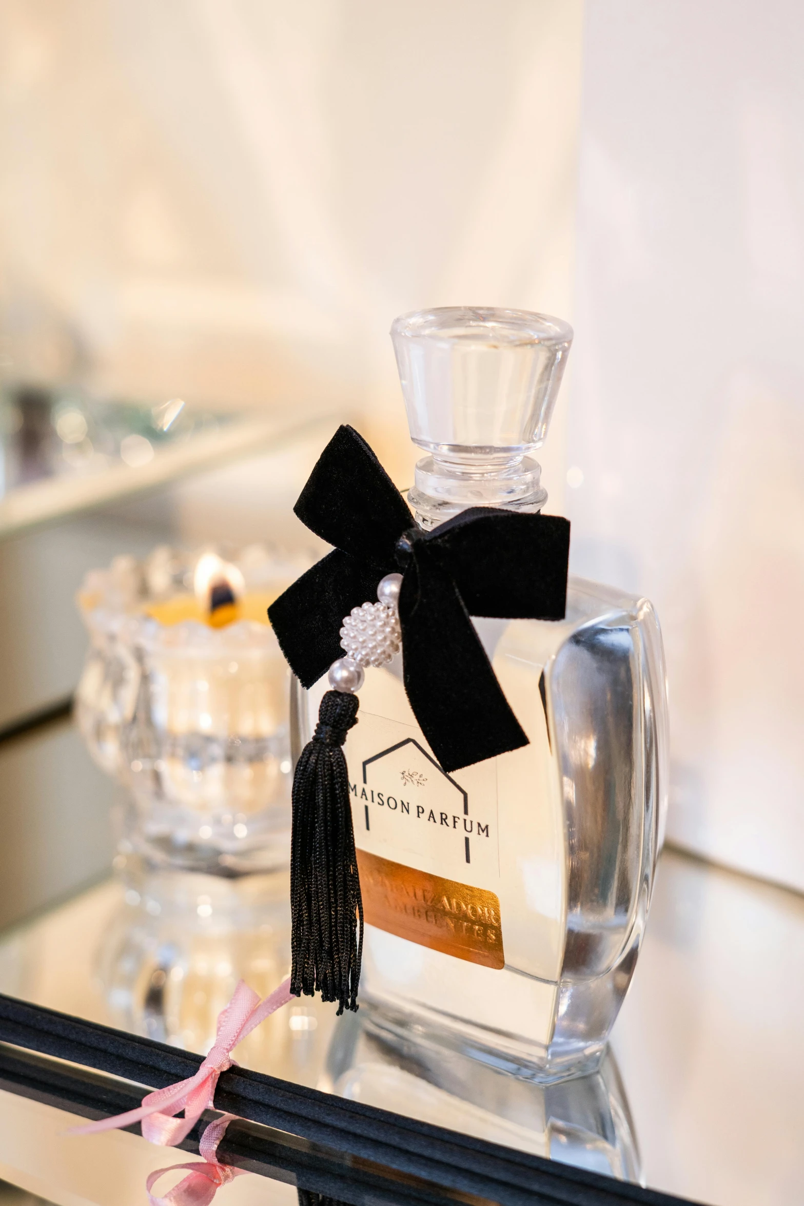 a bottle of perfume and a black ribbon tied with a pink ribbon