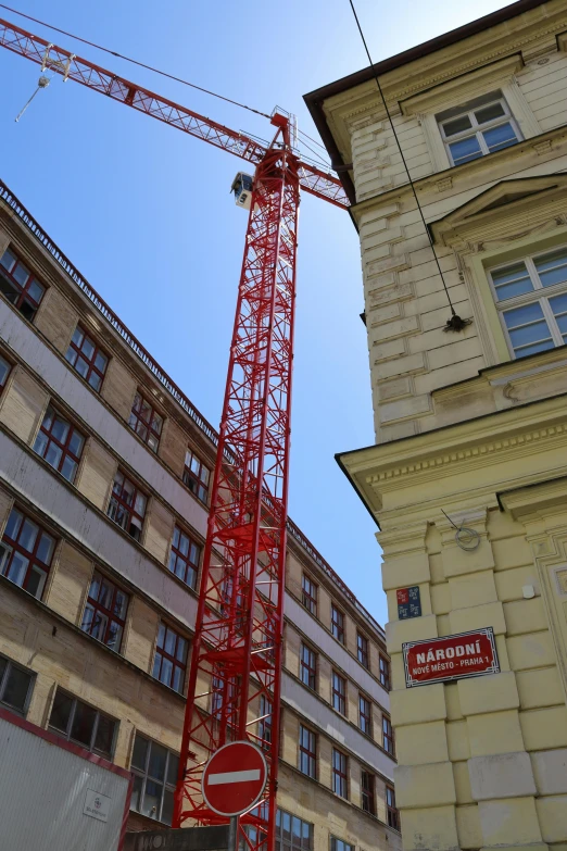 a tall red crane sitting next to a building