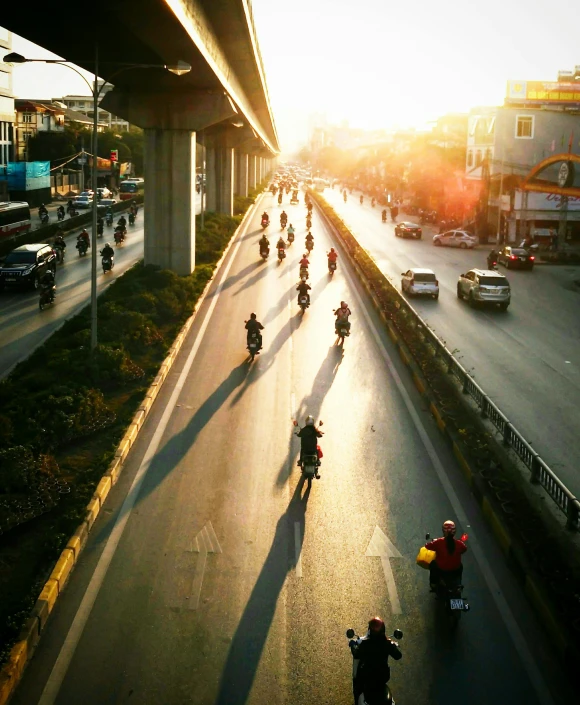 people ride bicycles down the highway with cars