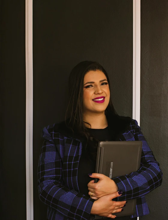 a woman standing in front of black background smiling for a picture