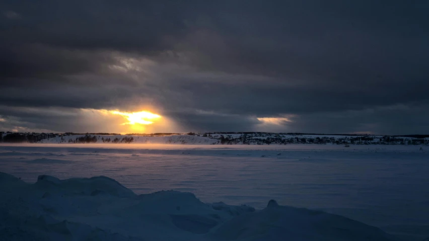 a cold and cloudy evening with the sun coming up over mountains