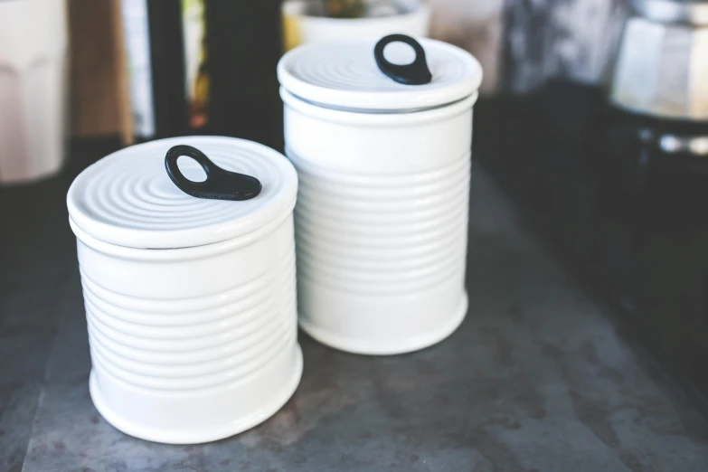 two canisters with a handle are on a black counter