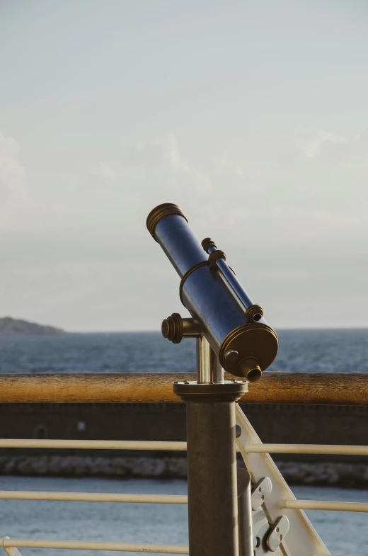 an telescope is on a railing overlooking the water