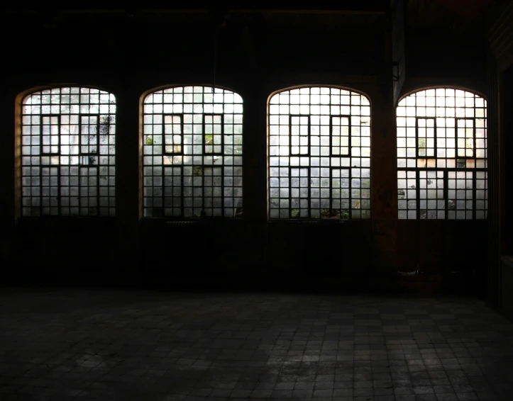 three windows are seen with light shining in the dark