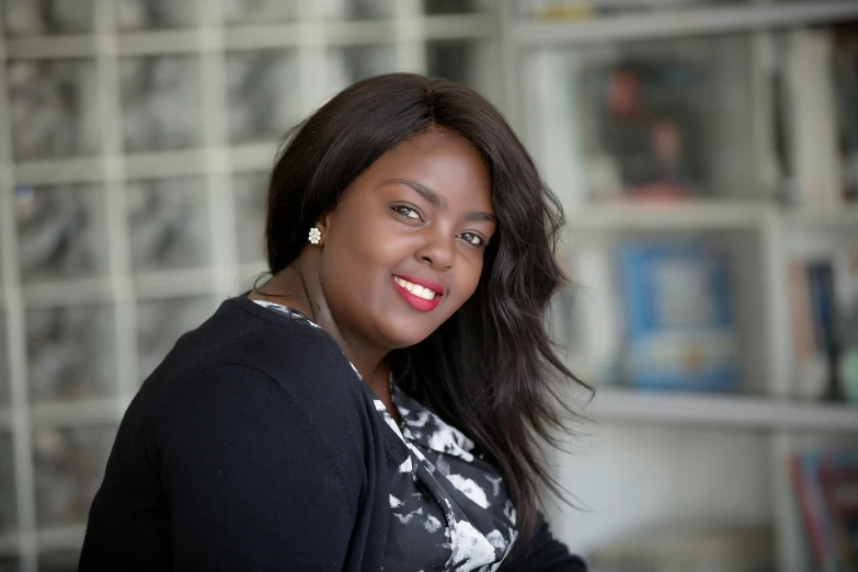 smiling woman with black jacket standing in front of shelves