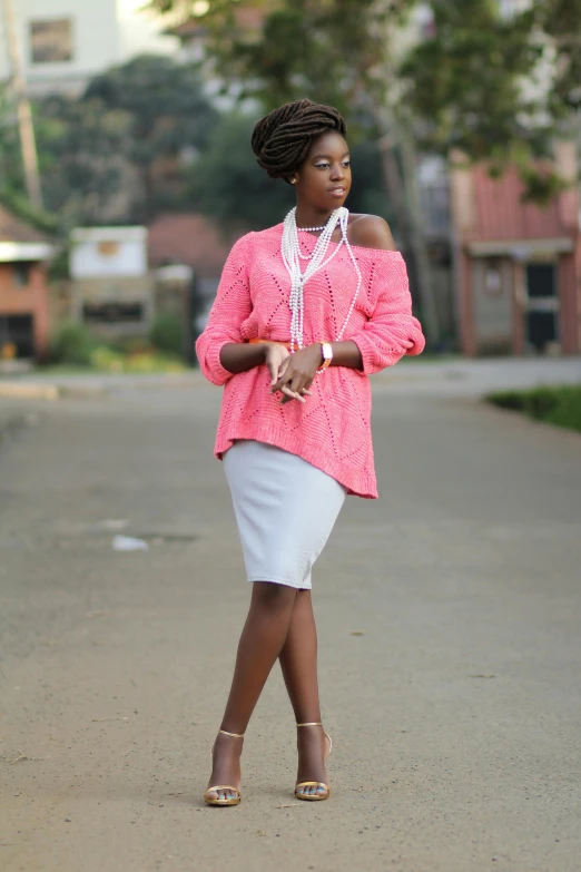 a woman in pink and white walking on a sidewalk