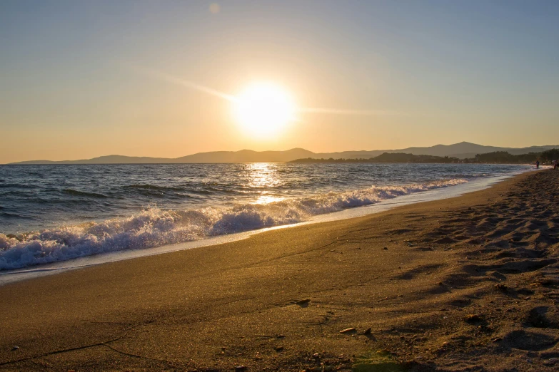 the sun is setting at the beach as it looks like it is about to be hit by a wave