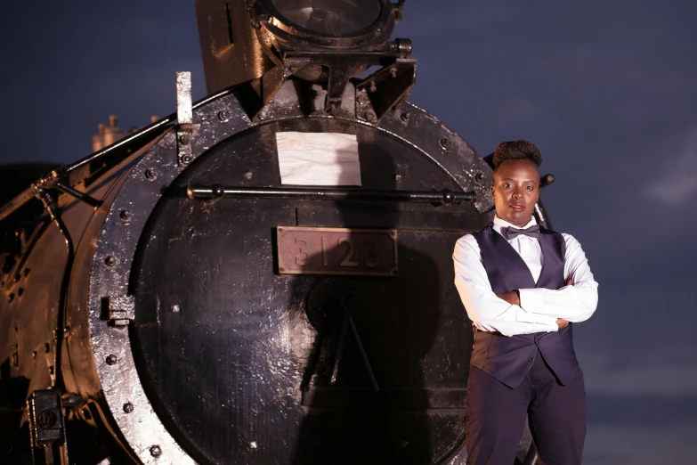 an african american woman standing beside an old fashioned steam locomotive