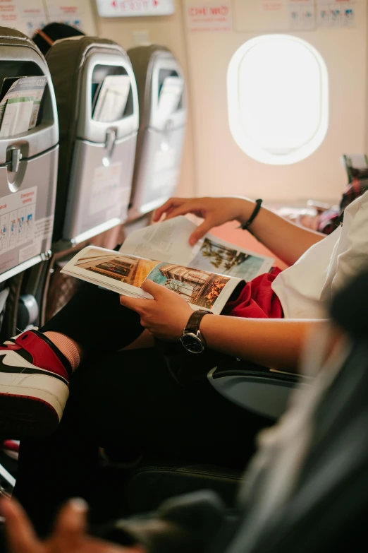 a person is sitting in a airplane reading a magazine