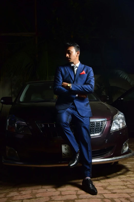 man in suit standing next to a parked car