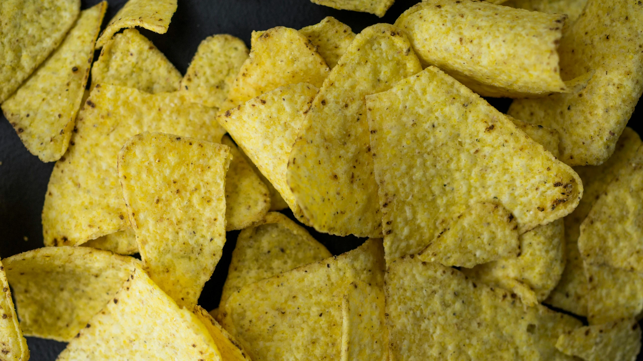 corn chips are on a plate and some are in the process of being eaten