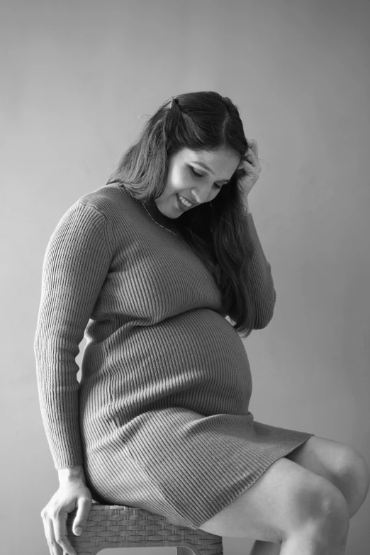 a woman sitting on a stool while posing