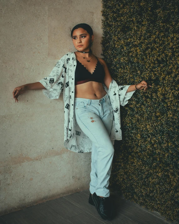 a beautiful woman in jeans leaning against a wall