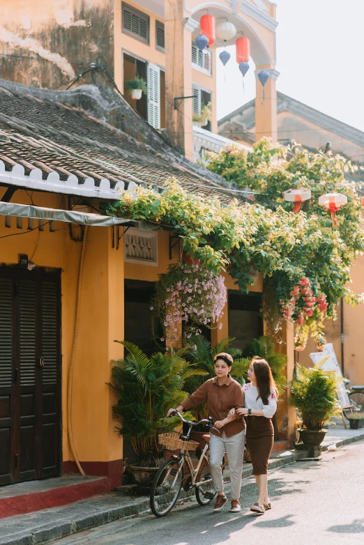 two people standing next to a yellow building