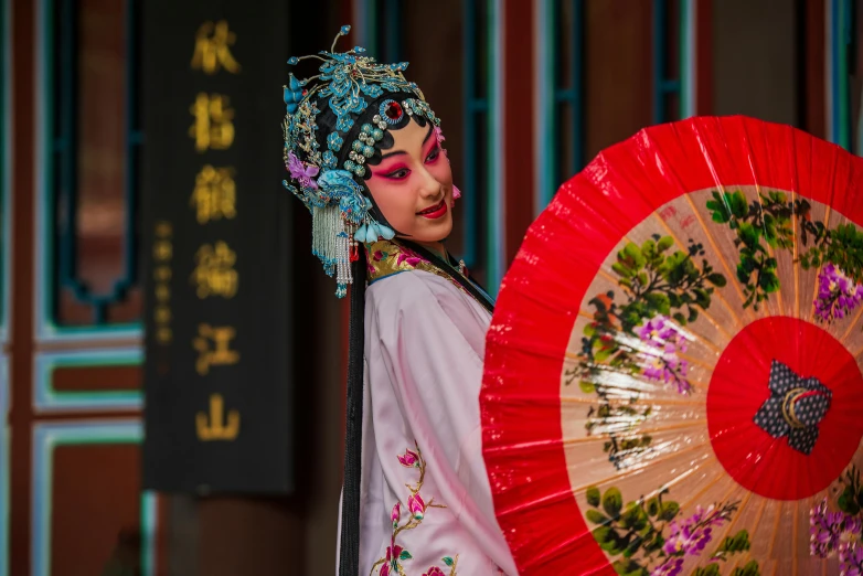 the geisha performer is holding a large decorative fan