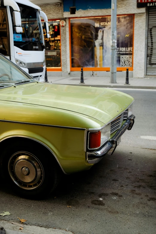 a green car parked on the street with a bus in the background