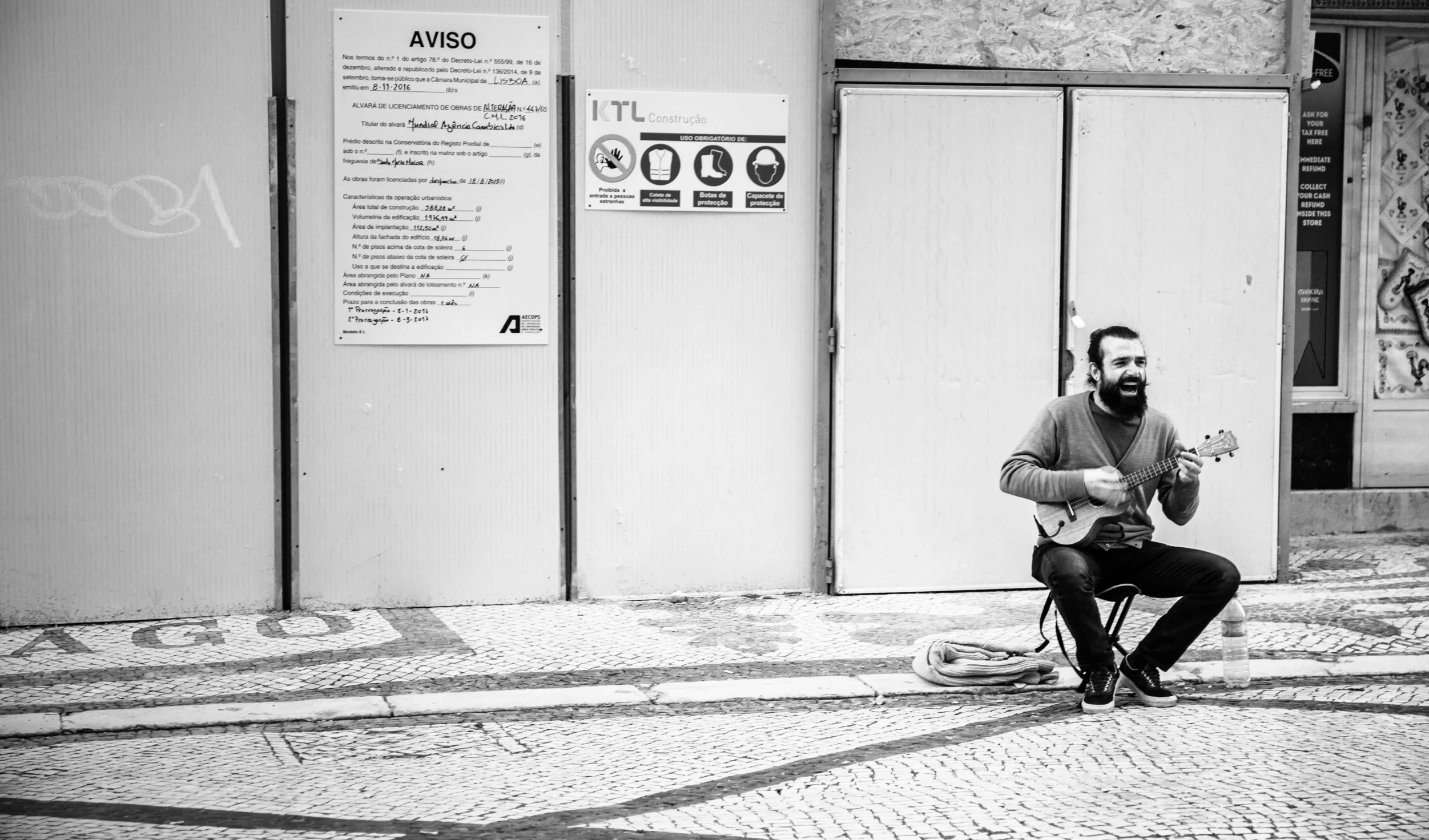 a black and white po of a man playing guitar in front of some doors