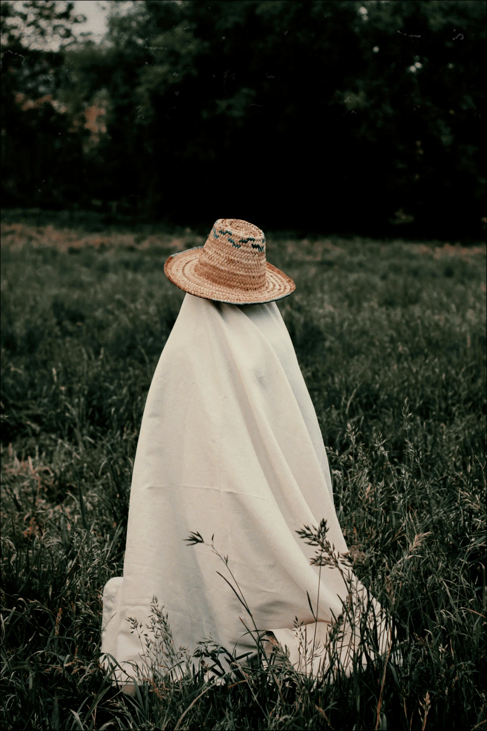 a woman with a white cloth covered face standing in tall grass