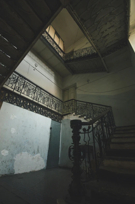 a po looking down at a stairwell with railing and a light in the dark